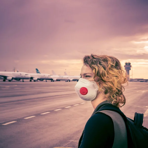 Vrouw wacht op check-in in de lobby van de luchthaven. Gebruikt mond- en neusmasker voor bescherming tegen virussen. Geannuleerde luchtdiensten als gevolg van een coronavirusepidemie — Stockfoto