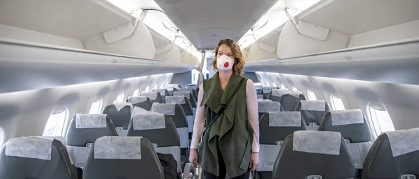 Kvinna ombord på flygplan med respirator på huvudet. skydda sig mot virussjukdomar. Människor avbryter resa utomlands på grund av coronavirus — Stockfoto