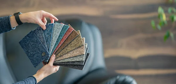 El hombre selecciona una nueva funda para el sofá del sampler de tarjetas de color —  Fotos de Stock