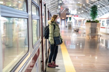 Metroda, kafasında tıbbi maske olan bir kadın var. Viral hastalıklara karşı koruma