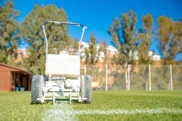 Tracciare linee bianche sul campo di calcio con vernice bianca sull'erba utilizzando una macchina speciale prima di una partita — Foto Stock