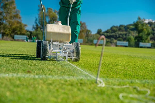 Narysowane białe linie na boisku piłkarskim z białą farbą na trawie przy użyciu specjalnej maszyny przed grą — Zdjęcie stockowe