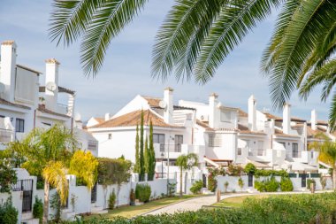 Turistler için beyaz villalar mevsim boyunca ziyaret edilmeyi bekliyor. Bulanık. Ön planda palmiye yaprakları