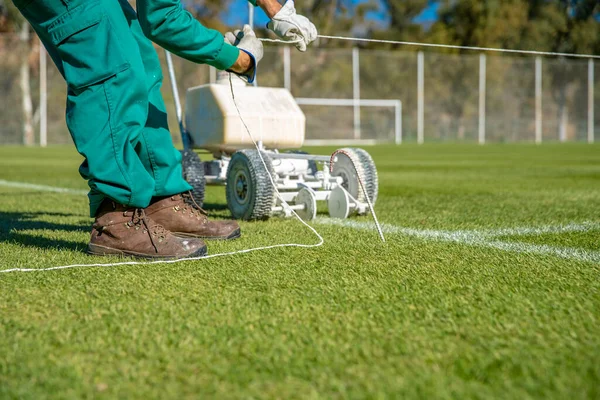 芝生の上に白い塗料を使用してサッカー場の裏地のためのロープを伸ばす — ストック写真