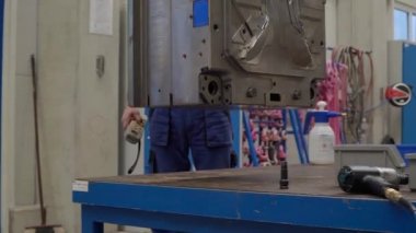 Fabrikada vinç ile ağır metal inşaatı, teknisyen uzaktan kumandayla vinci kontrol ediyor.