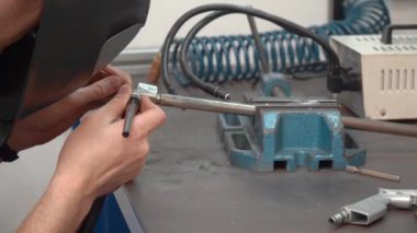 Atölyedeki metali kaynak yaparken yüzünde koruyucu maskeli bir adam vardı. Otomotiv endüstrisi için üretim