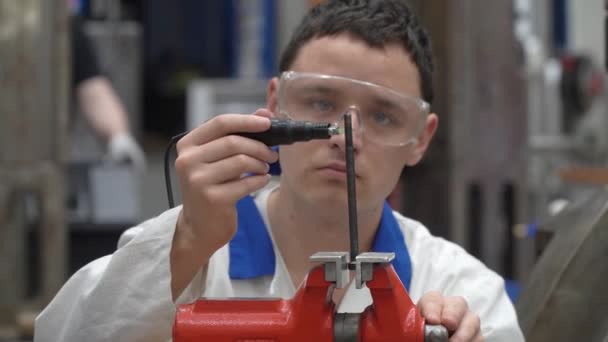 Joven técnico en una fábrica reparando una máquina. hombre utiliza una vise para trabajar en la fábrica — Vídeo de stock