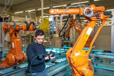 Üretim mühendisi bir fabrikanın üretim hattında robotik silahları programlıyor.