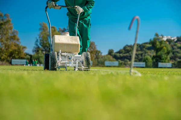 Spruzzare vernice bianca sull'erba per aiutare la macchina a segnare i confini di un campo di calcio . — Foto Stock