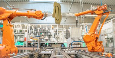 Turuncu robot kollar üretim hattında. Yapay zekaya sahip bir bilgisayar tarafından kontrol ediliyor.