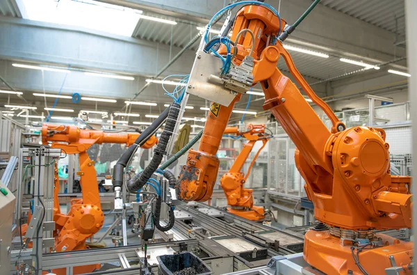 Turuncu robot kollar üretim hattında. Yapay zekaya sahip bir bilgisayar tarafından kontrol ediliyor.