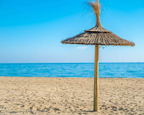 Солом'яна парасолька на березі моря, блакитне небо — стокове фото