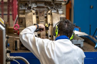 Mühendis, özel bir makine kullanarak kalıbın donmasını gerçekleştiriyor. Fabrikadaki plastik kalıplar için metal kalıpların bakımı