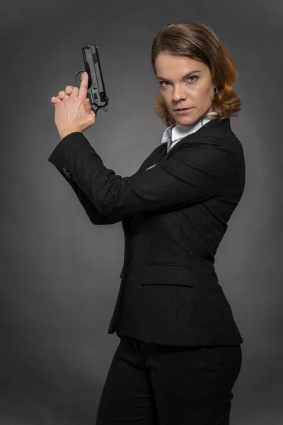 Portrét ženy s pistolí na černém pozadí — Stock fotografie