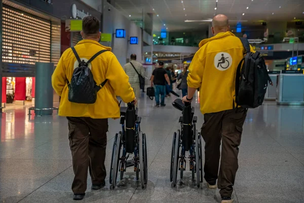 구조 대가 공항에 있는 휠체어에 장애 인을 태우고 이동하는 모습 — 스톡 사진