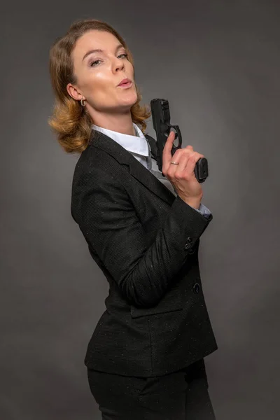 Portrét ženy s pistolí na šedém pozadí — Stock fotografie