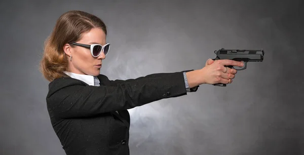 Woman holding gun with both hands and aiming at target — Stock Photo, Image
