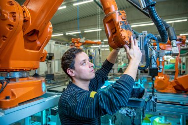 Robotun yeni bir ürün üretmesi için modifiye edilmesi. Teknik olarak, işçi makineyi ayarlar. konsept sektörü 4.0