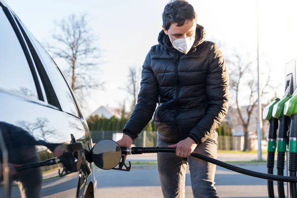 Tanken van de auto op het moment van de epidemie coronavirus met een beademingsapparaat over zijn mond en neus — Stockfoto