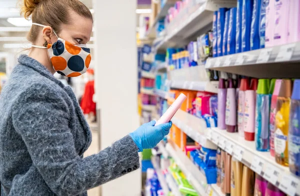 Mujer comprando cosméticos en un centro comercial con una máscara de salud en la cara durante una epidemia de coronavirus — Foto de Stock