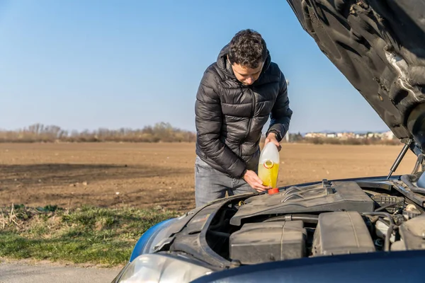 Man pours into the car yellow liquid for the wiper — Stock Photo, Image