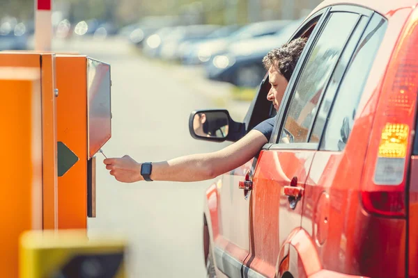 Мужчина берет парковочный талон при въезде на платную парковку на машине — стоковое фото