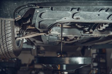 Araba tamir atölyesindeki motor yağının boşaltılması.