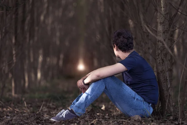 Ein nachdenklicher Mann im Wald blickt zum Licht auf in der Hoffnung auf bessere Zeiten. Kopierraum — Stockfoto