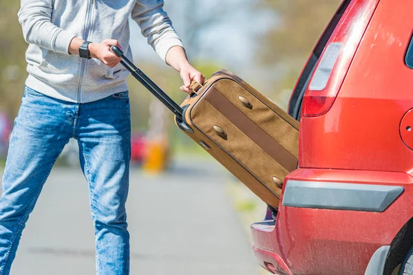 Un joven saca su equipaje del maletero de un coche — Foto de Stock