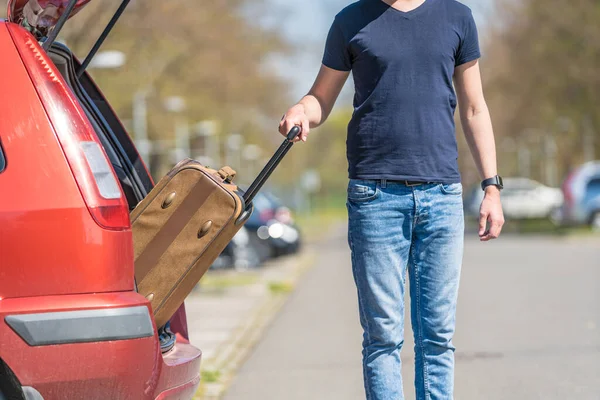 젊은 남자가 차 트렁크에서 짐을 꺼내 — 스톡 사진