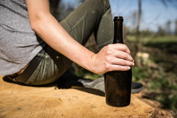 Ένα μπουκάλι κρασί στο χέρι ενός άντρα, πίνοντας αλκοόλ στη φύση — Φωτογραφία Αρχείου