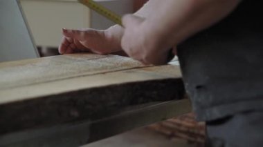 Bir adam doğramacıda dairesel testere ile odun kesiyor.