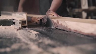 Bir adam doğramacıda dairesel testere ile odun kesiyor.