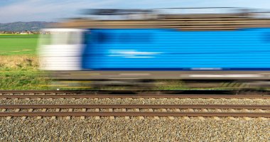Elektrikle çalışan mavi tren, kırsal alandan geçiyor. Bulanık