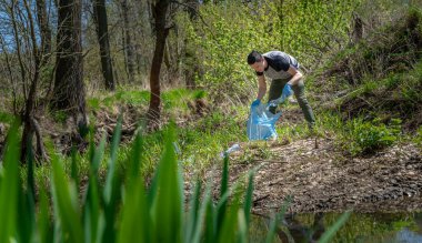 Plastik atık ile gezegenin küresel kirliliği. Gönüllüler atık toplayarak ormanları ve çayırları temizleyerek ekolojiye yardım ediyor