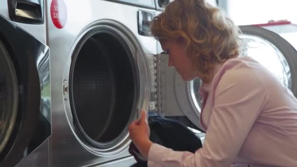 把脏衣服放进洗衣房的洗衣机里。年轻妇女在家里打扫卫生 — 图库视频影像