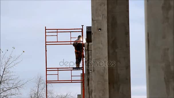 A welder working at height in the construction of large shopping complex metal structures and concrete piles — Stock Video