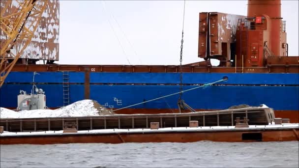 O processo de carregamento de carvão da barcaça para o navio no rio com a ajuda do guindaste de carga portuária . — Vídeo de Stock