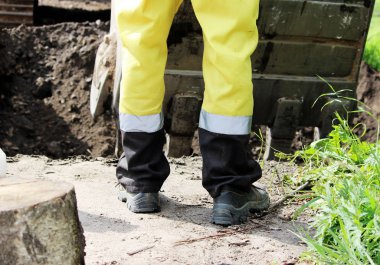 İnşaat işçisi yol kenarını genişletirken kazıcıyı yönetiyor..