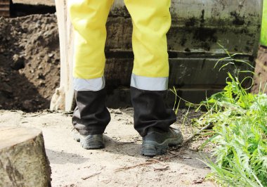 İnşaat işçisi yol kenarını genişletirken kazıcıyı yönetiyor..