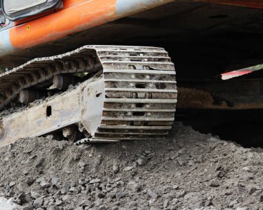 Ağır turuncu sürüngen kazıcısı, yolun onarım ve genişleme alanının üzerinde duruyor.