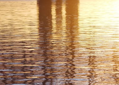 Arka planda batan güneşin altın ışınlar nehrindeki su. Maviye altın