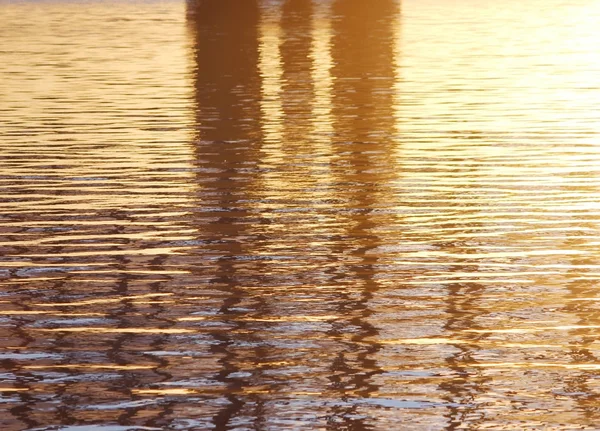 Arka planda batan güneşin altın ışınlar nehrindeki su. Maviye altın