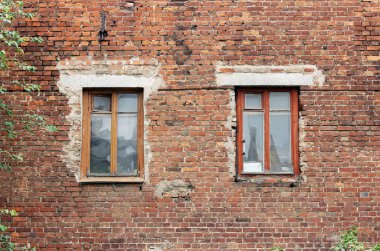 Eski tuğla duvar ve arka planda iki pencere.