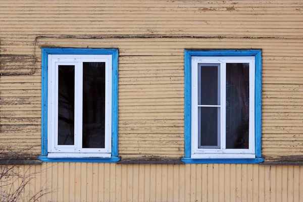 Dos ventanas en el azul enmarcadas en una casa de madera, pintura beige pintada — Foto de Stock