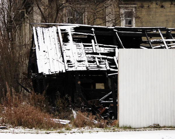 Black and white photo snowy abandoned burned-out fire wooden house. — Stock Photo, Image