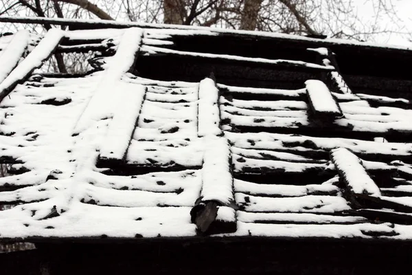 snowy abandoned burned-out fire wooden house.