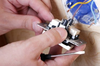 İşçi elektrikçi dairedeki hasarlı prizleri tamir ediyor.