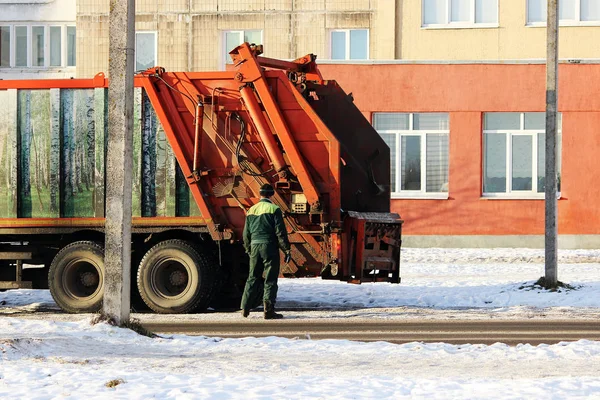 Працівник стоїть поруч з непотрібним автомобілем після завантаження сміттєвого бака . — стокове фото