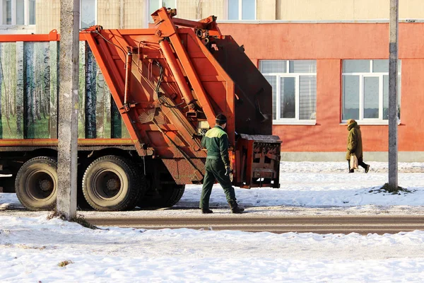 Працівник стоїть поруч з непотрібним автомобілем після завантаження сміттєвого бака . — стокове фото